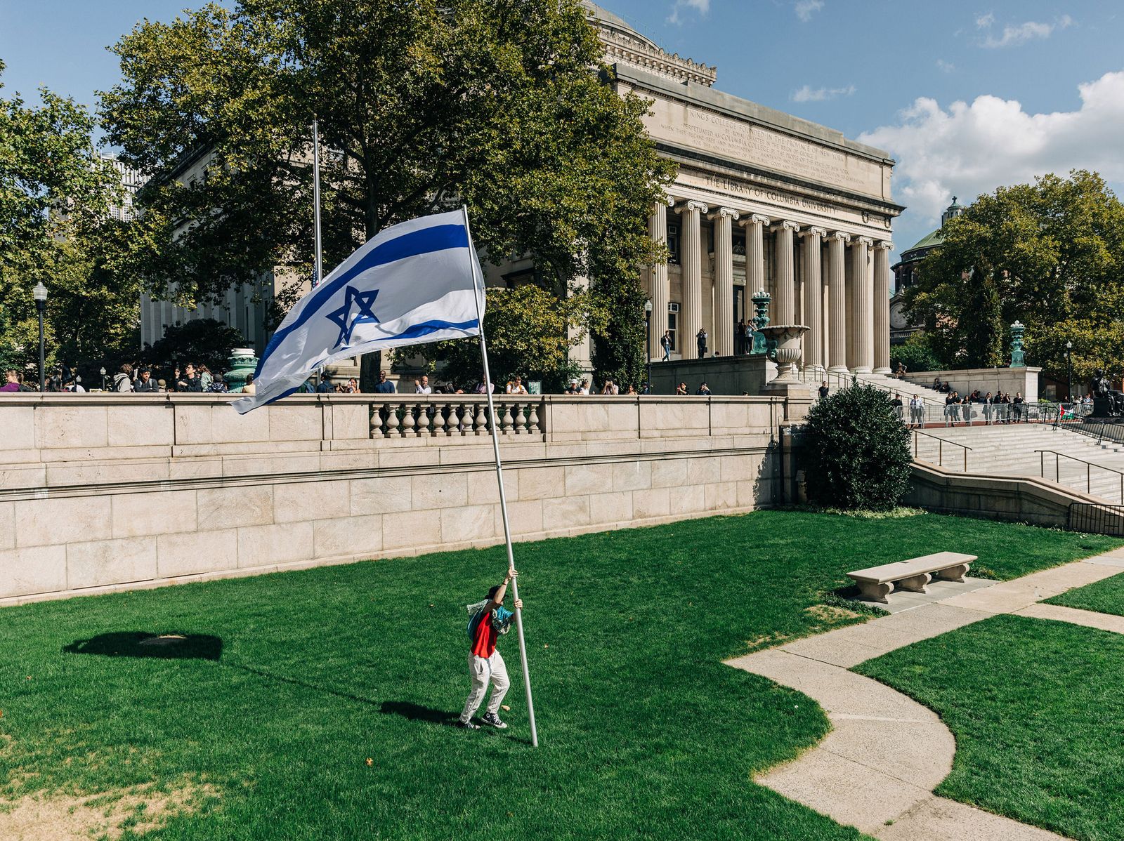A man planting a pole with an Israeli flag on the lawn of Columbia University.