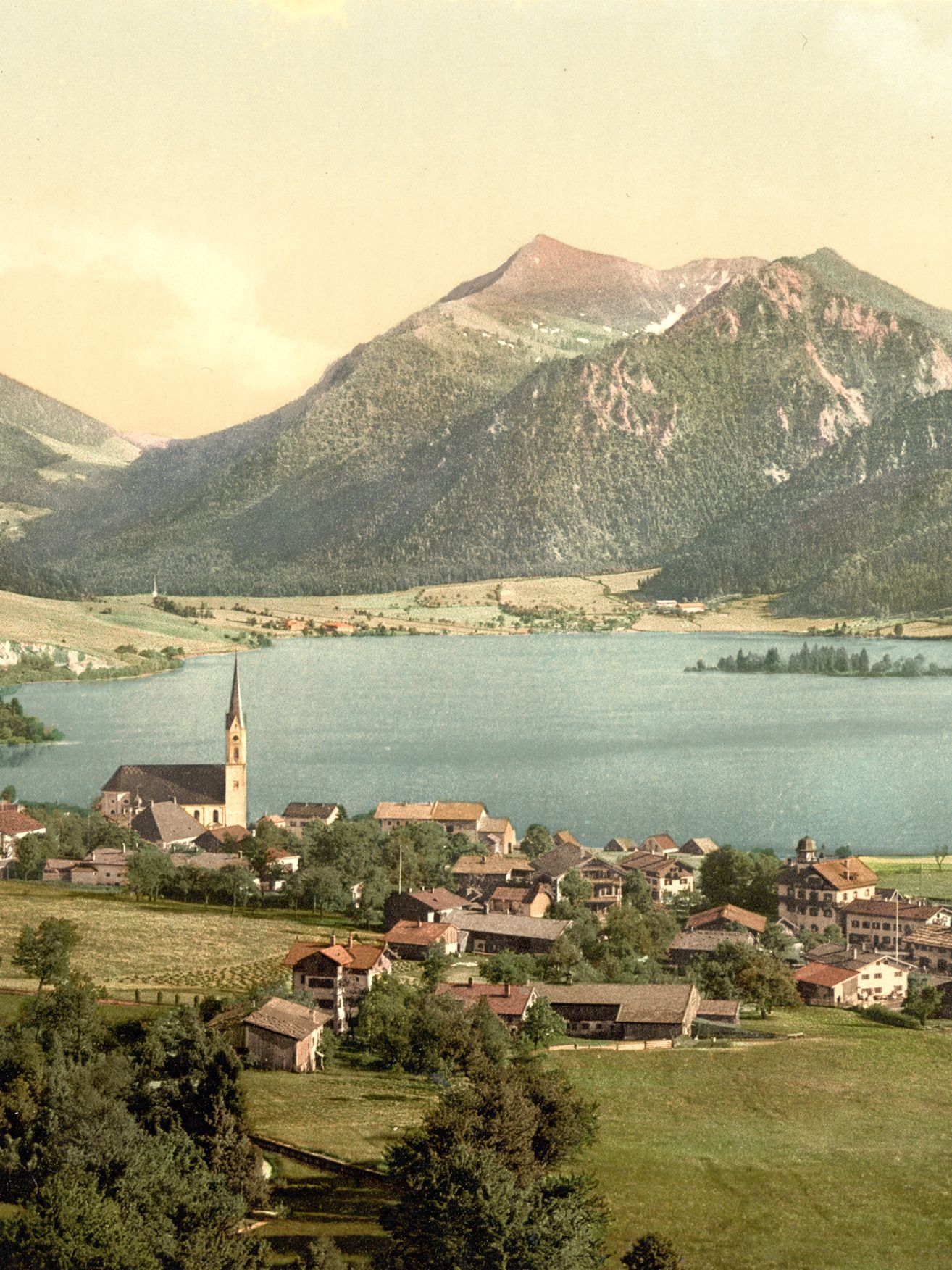Landscape of small town set against a lake. Mountains are set in the distance.