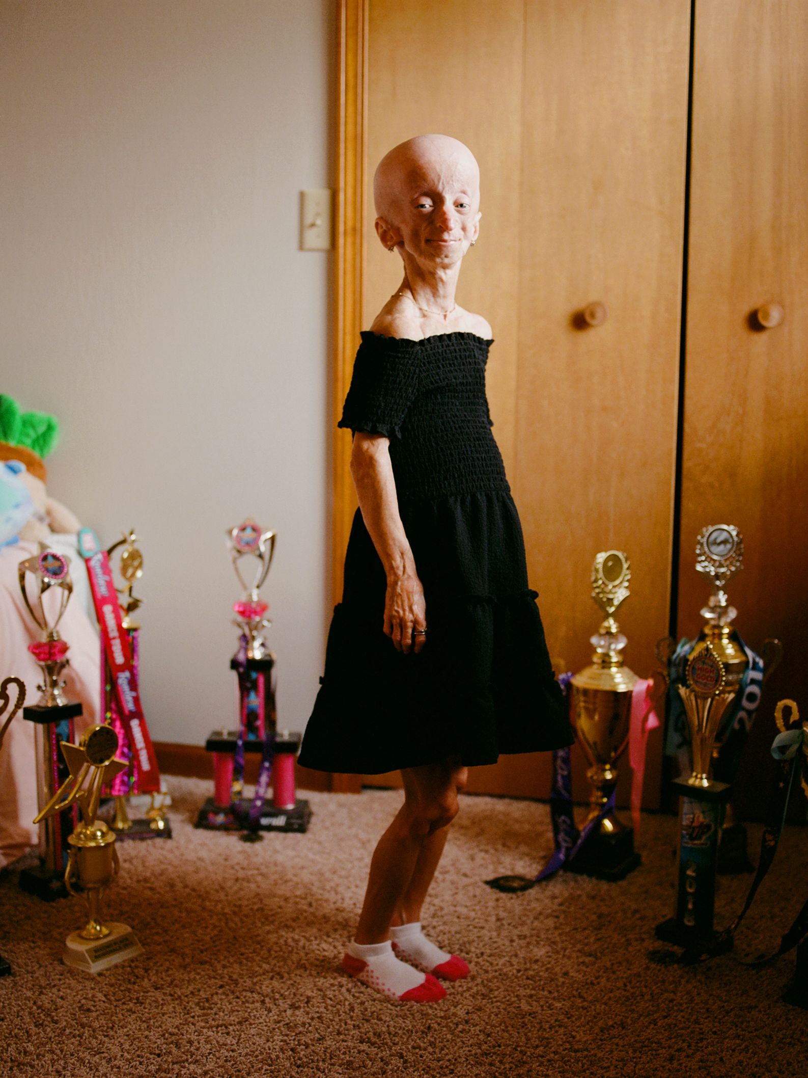 A person stands in a circle of trophies.
