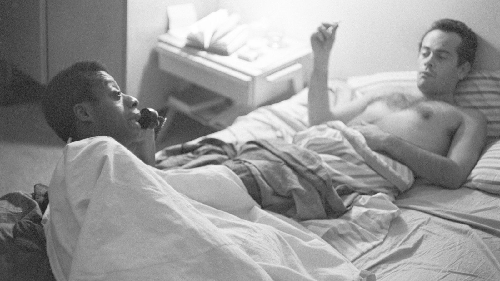 Two men lying in a bed.